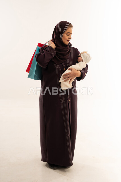 أم عربية مع رضيع وحقائب تسوق في الاستوديو