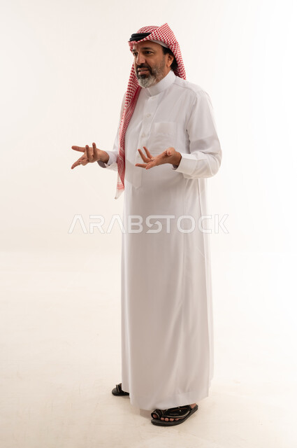 رجل سعودي بالزي التقليدي يشير بيديه في الاستوديو