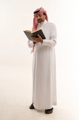 رجل سعودي يقرأ كتاباً في الاستوديو على خلفية بيضاء