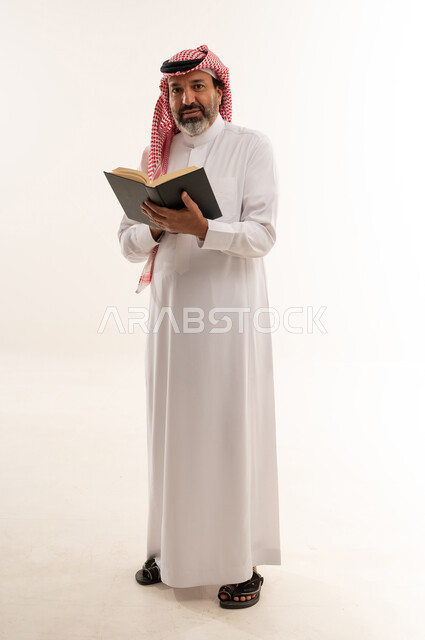 رجل سعودي يمسك كتاباً بخلفية بيضاء