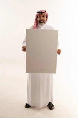 رجل سعودي بالزي التقليدي يمسك لوحة بيضاء فارغة