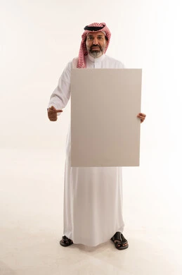 رجل سعودي يحمل لوحة بيضاء فارغة في استوديو