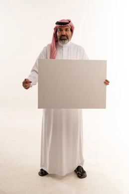 رجل سعودي يحمل لوحة بيضاء فارغة في استوديو تصوير