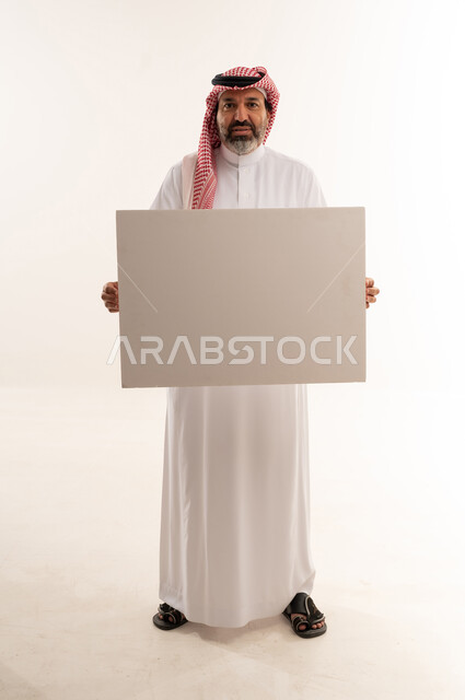 رجل سعودي بالزي التقليدي يحمل لوحة فارغة