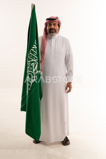 رجل سعودي يمسك بالعلم السعودي في الاستوديو