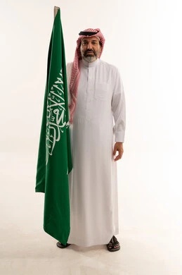 رجل سعودي يمسك بالعلم السعودي في الاستوديو