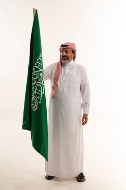رجل سعودي يحمل العلم الوطني في استوديو أبيض