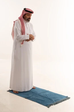 رجل سعودي يصلي على سجادة صلاة خلفية بيضاء