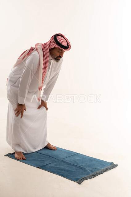 Saudi Man Performing Prayer Bowing Position on Rug
