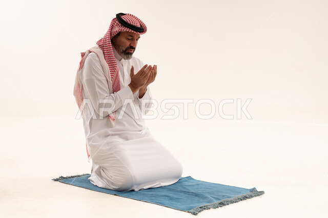 رجل سعودي يصلي ويدعو على خلفية بيضاء