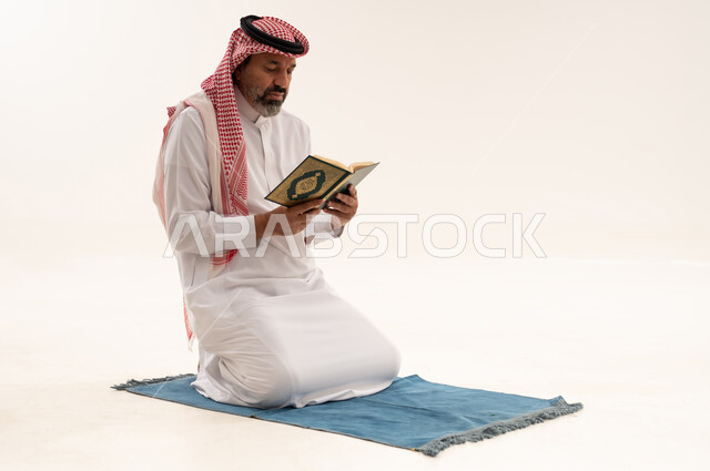 Saudi Man Reading Holy Quran on Prayer Mat