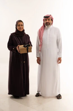 زوجان سعوديان مع صندوق هدايا على خلفية بيضاء