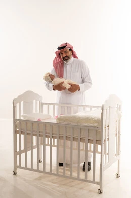 أب سعودي يحمل مولوداً جديداً في استوديو أبيض