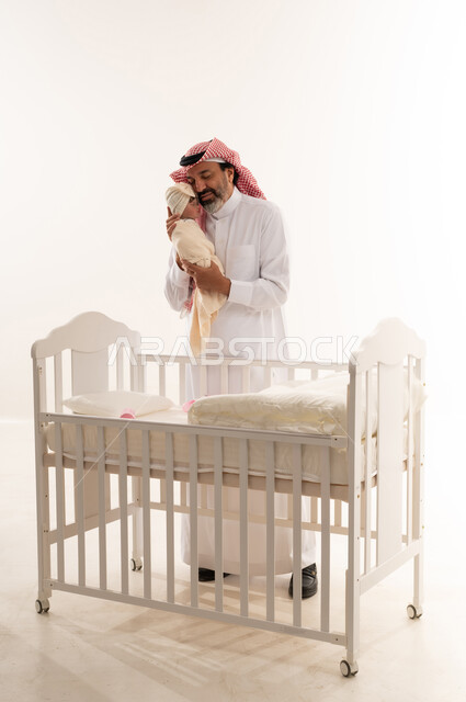 Saudi Father Holding Newborn Baby Near White Crib