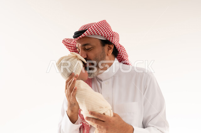 أب سعودي يقبل طفله حديث الولادة في الاستوديو