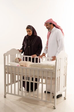 والدان سعوديان مع مولود جديد في سرير أبيض