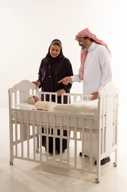 زوجان سعوديان يقفان بجانب سرير طفل في استوديو