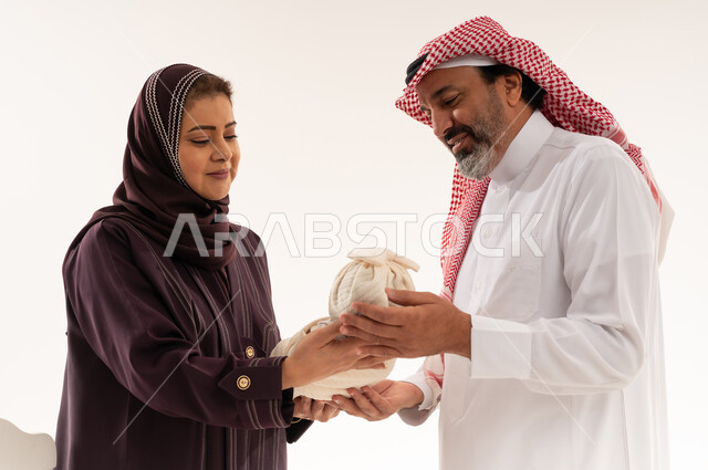 زوجان سعوديان بالزي التقليدي يمسكان حقيبة قماشية