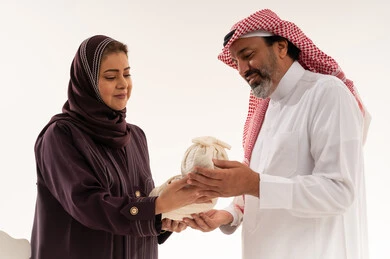Saudi Couple in Traditional Attire Holding Small Bag