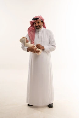 رجل سعودي يحمل طفلاً حديث الولادة في الاستوديو