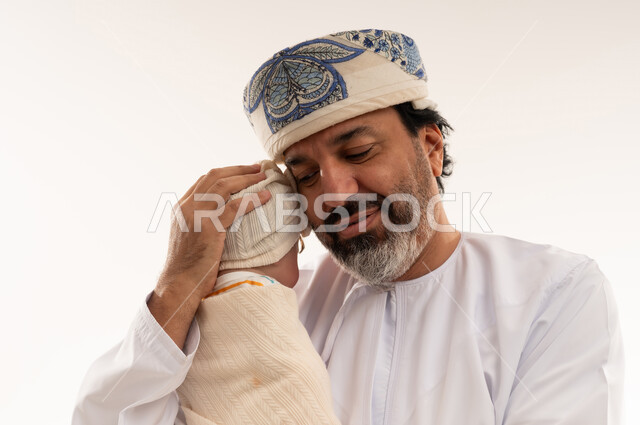 رجل عماني بالزي التقليدي يحمل طفلاً حديث الولادة