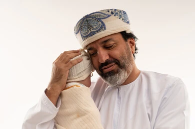 رجل عماني بالزي التقليدي يحمل طفلاً حديث الولادة