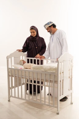 Omani Couple with Newborn Baby in White Crib