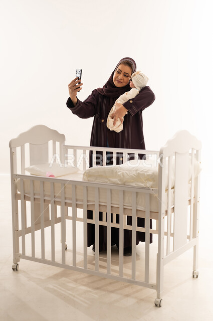 Saudi Mother Taking Selfie with Newborn by Crib