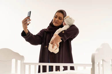Arab Mother with Newborn Baby Taking Smartphone Selfie