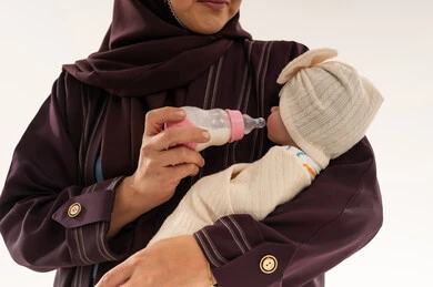 امرأة سعودية تطعم طفلاً رضيعاً بزجاجة الحليب