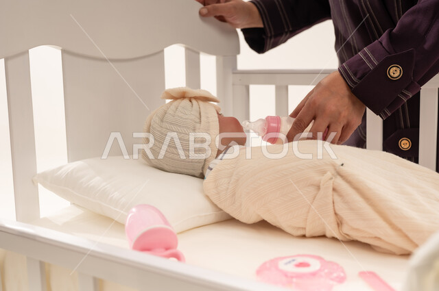 Arab Woman Feeding Newborn Baby in White Crib