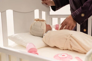 امرأة عربية تطعم طفلاً رضيعاً في سرير أبيض