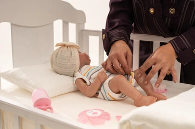 امرأة تعتني بدمية طفل داخل سرير أبيض