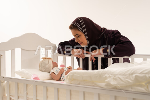 أم عربية تنظر إلى مولودها الجديد في سرير أبيض