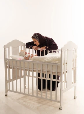 أم سعودية مع طفلها في سرير أبيض خلفية استوديو