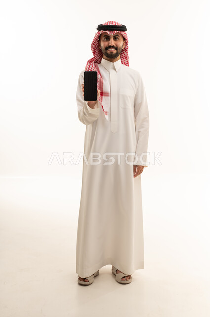 Saudi Man in Traditional Thobe Holding a Smartphone Studio