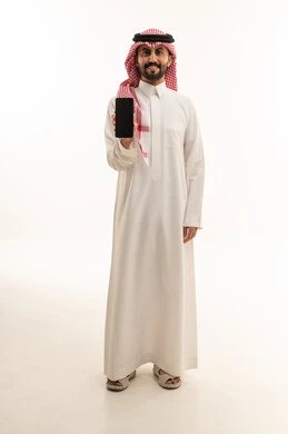 Saudi Man in Traditional Thobe Holding a Smartphone Studio