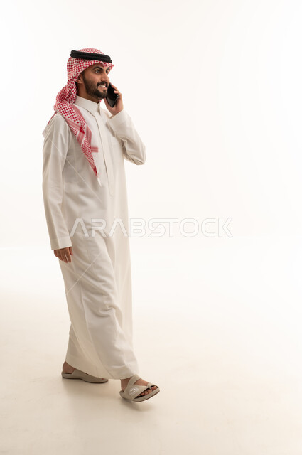 رجل سعودي يتحدث عبر الجوال بزي تقليدي في الاستوديو
