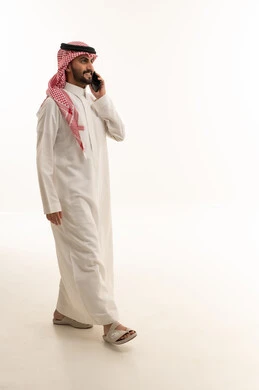 رجل سعودي يتحدث عبر الجوال بزي تقليدي في الاستوديو