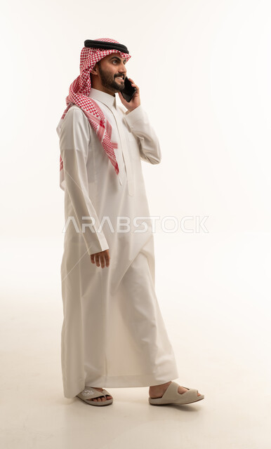 Saudi Man in Thobe Talking on Phone Studio White Background