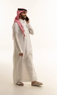 رجل سعودي بالثوب يتحدث في الهاتف في استوديو بخلفية بيضاء