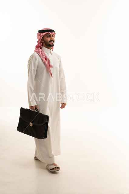 رجل أعمال سعودي يسير بحقيبة في الاستوديو