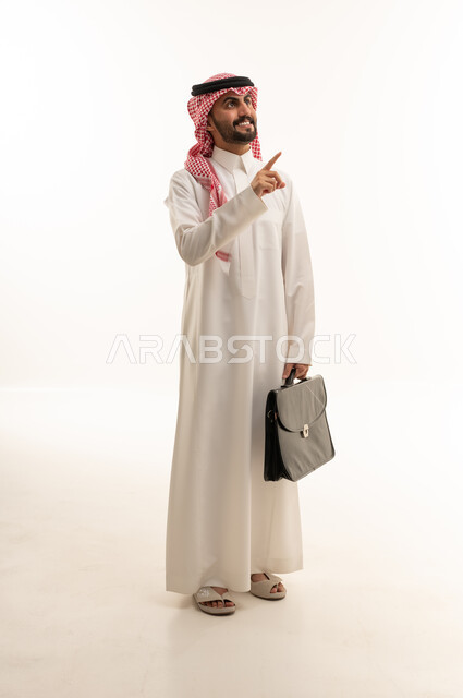 رجل أعمال سعودي يشير بيده مع حقيبة عمل