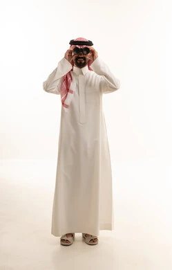 رجل سعودي بالثوب ينظر من خلال المنظار