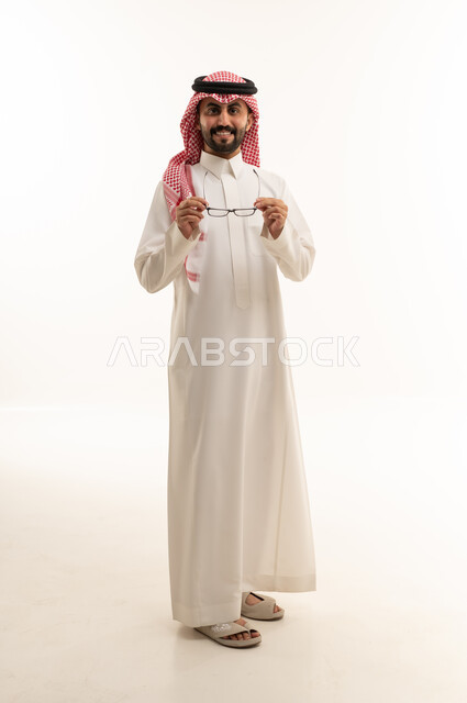 رجل سعودي بالثوب التقليدي يمسك بنظارة طبية