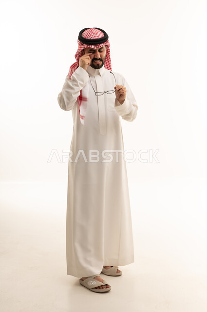 رجل سعودي بالزي التقليدي يفرك عينيه من التعب