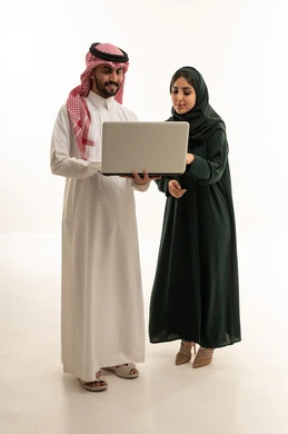 رجل وامرأة سعوديان يستخدمان الكمبيوتر في استوديو أبيض