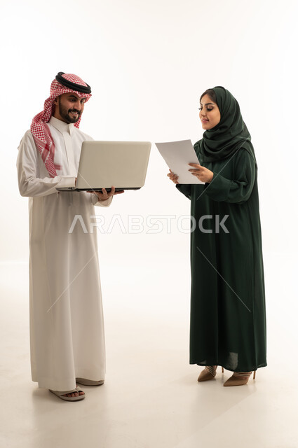 زملاء عمل سعوديون يناقشون العمل مع كمبيوتر محمول