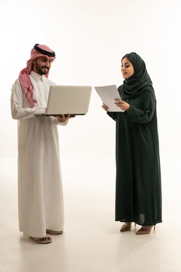 زملاء عمل سعوديون يناقشون العمل مع كمبيوتر محمول