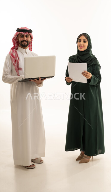 زملاء عمل سعوديين مع كمبيوتر محمول وأوراق